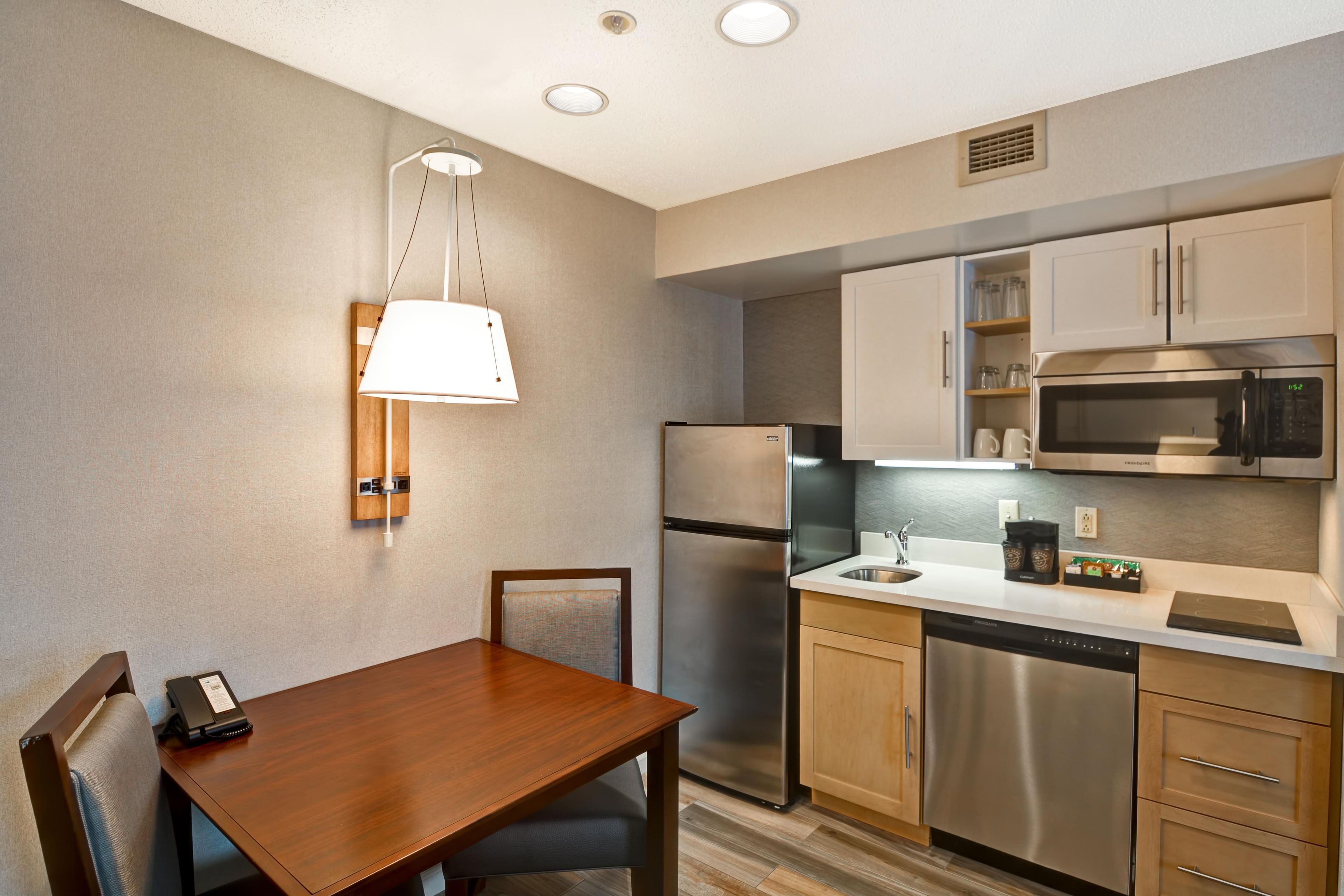 A modern kitchen with stainless steel appliances, a wooden dining table, and a pendant light.