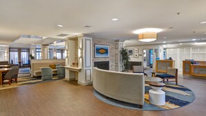Een ruime lobby met een gebogen bank, een receptiebalie en een open haard.