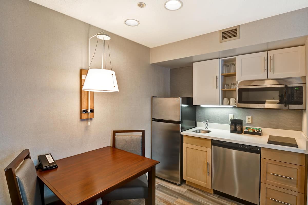 Una cocina moderna con electrodomésticos de acero inoxidable, una mesa de comedor de madera y una lámpara colgante.