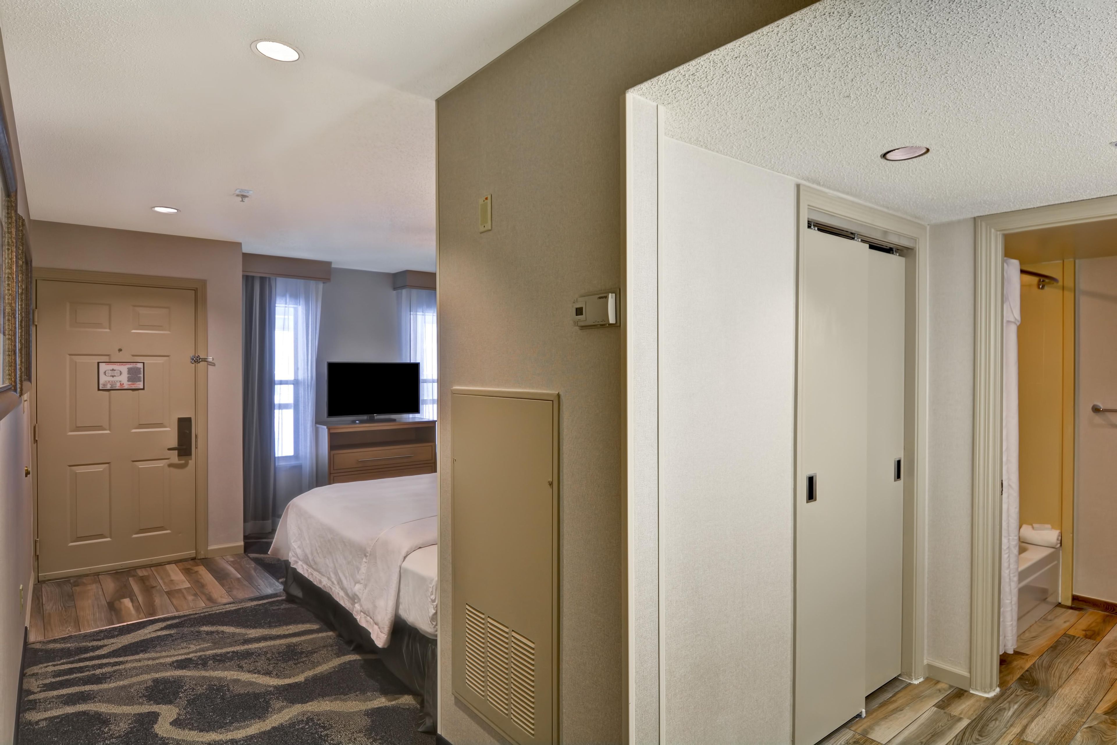 A hotel room with a bed, a television, a wardrobe, and a bathroom visible through an open door.