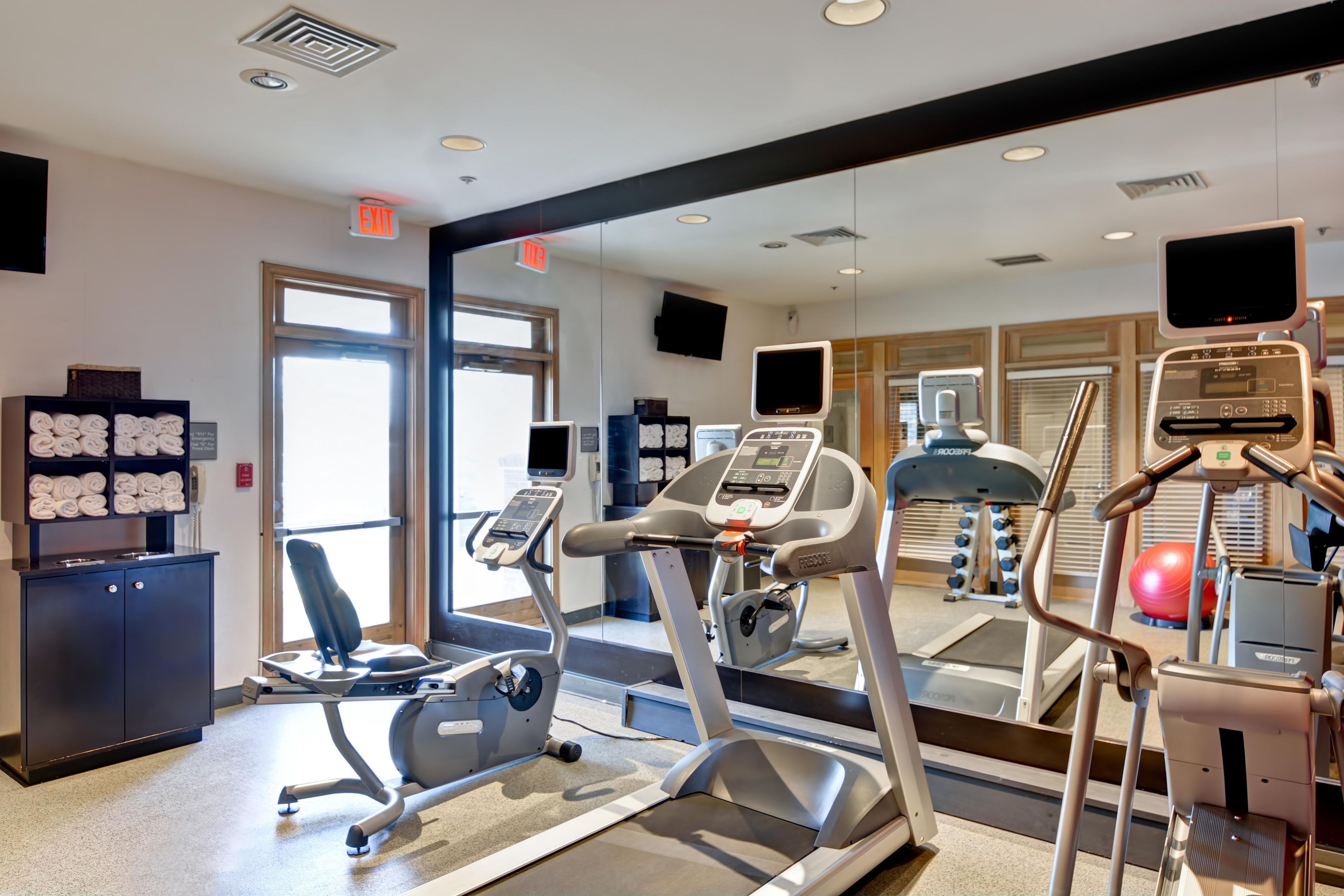 A gym with exercise equipment, a mirror, and a towel rack.