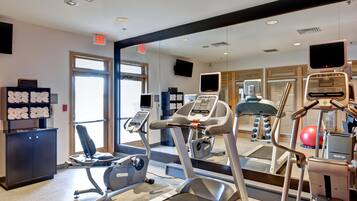 A gym with exercise equipment, a mirror, and a towel rack.
