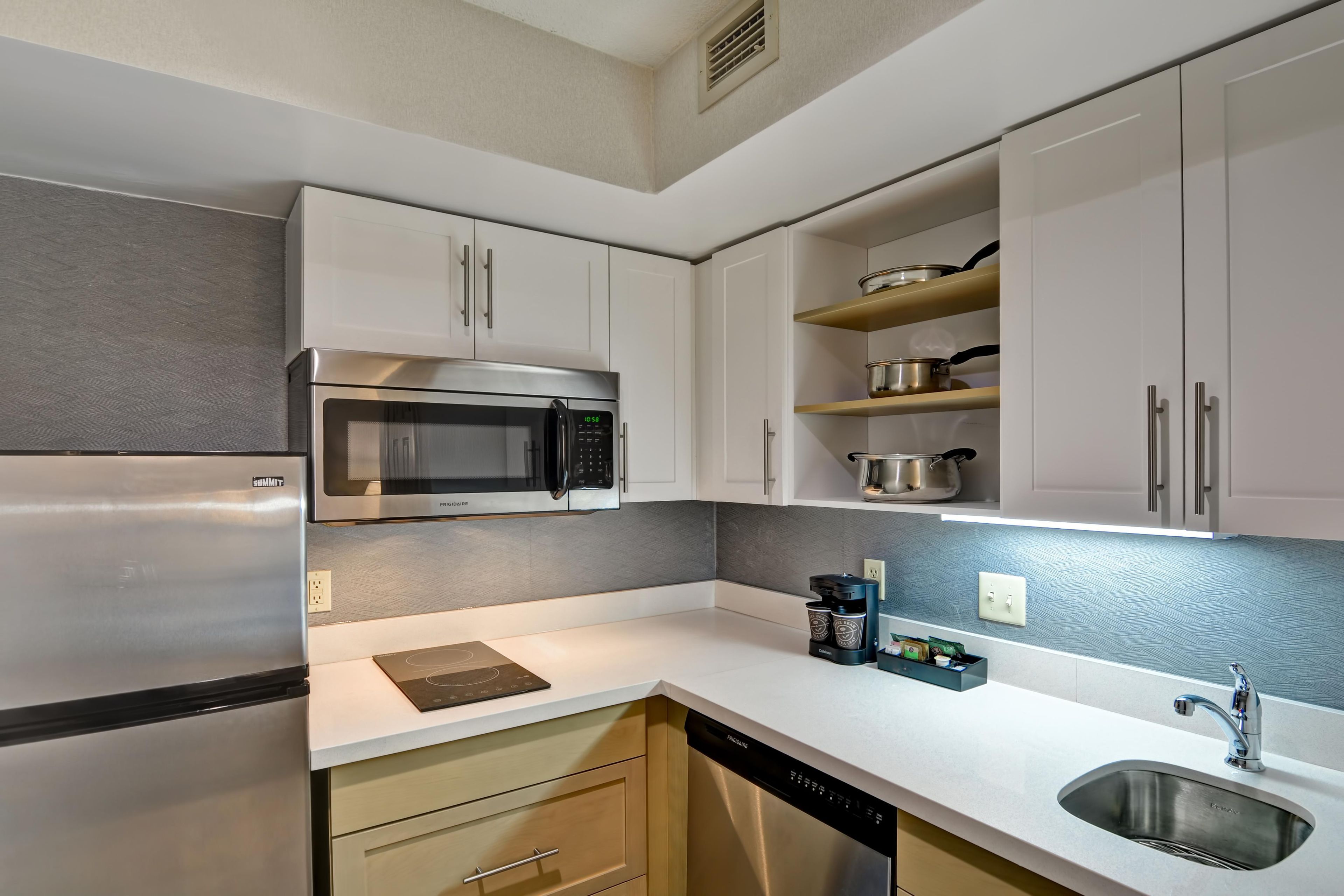 A modern kitchen with stainless steel appliances, white cabinetry, and a built-in dishwasher.