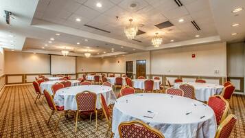 A conference room with round tables and red chairs, equipped with nameplates and pens.