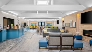 A spacious living area with a kitchen, seating, and a fireplace. - Country Inn & Suites by Radisson, Muskegon, MI (Muskegon)