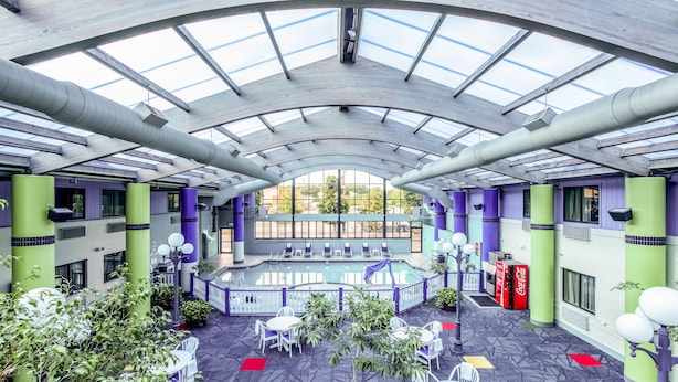 A spacious indoor area with a high ceiling, large windows, and seating arrangements. - Country Inn & Suites by Radisson, Muskegon, MI (Muskegon)