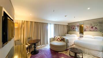 Una habitación de hotel con una cama, un sofá, una mesita, una silla y un espejo grande.