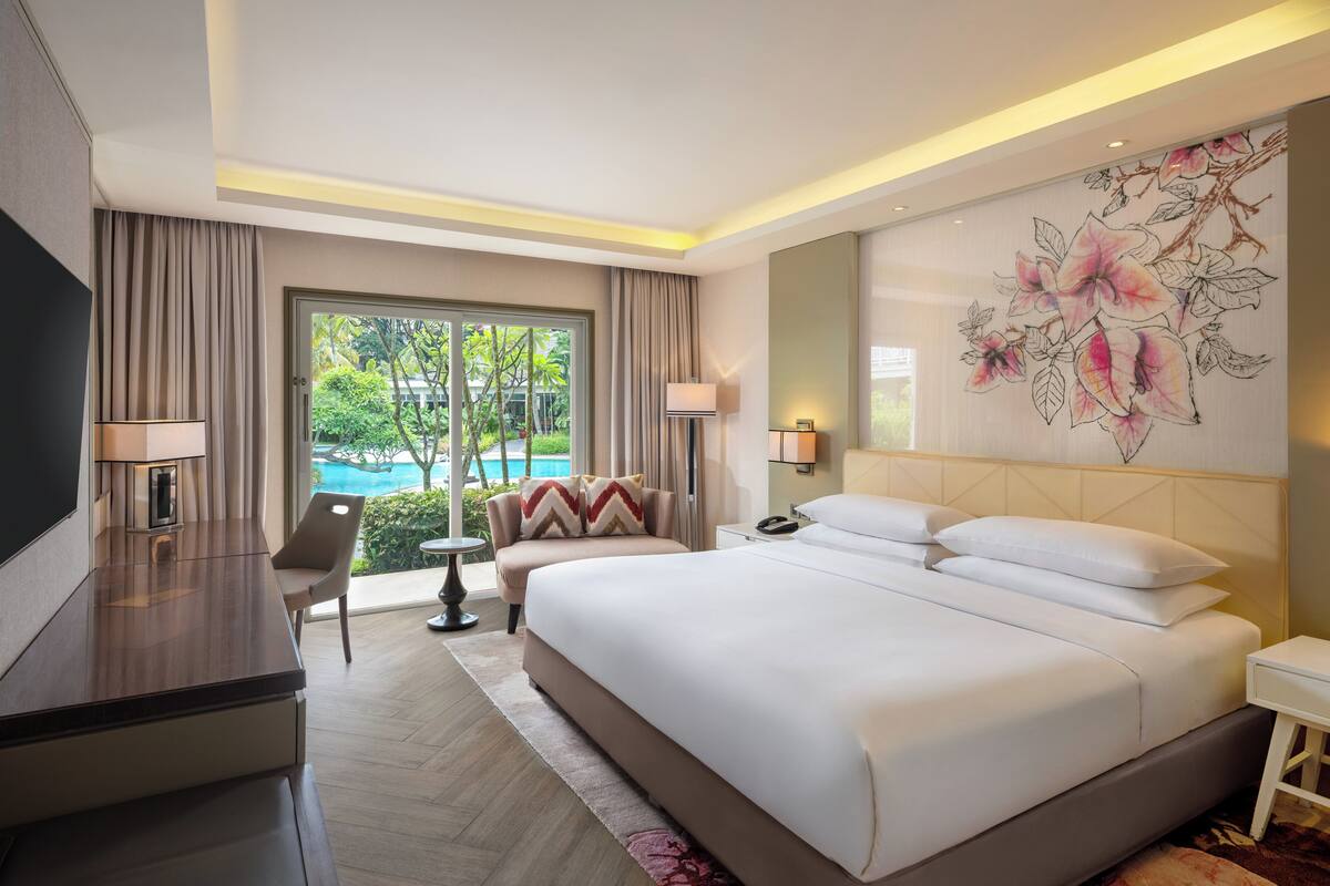 Une chambre d’hôtel moderne avec un grand lit, un bureau et une vue sur une piscine.