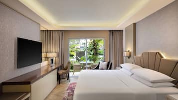 Habitación de hotel moderna con una cama grande, un televisor de pantalla plana montado en la pared, un escritorio con una lámpara y vistas al jardín por la ventana.
