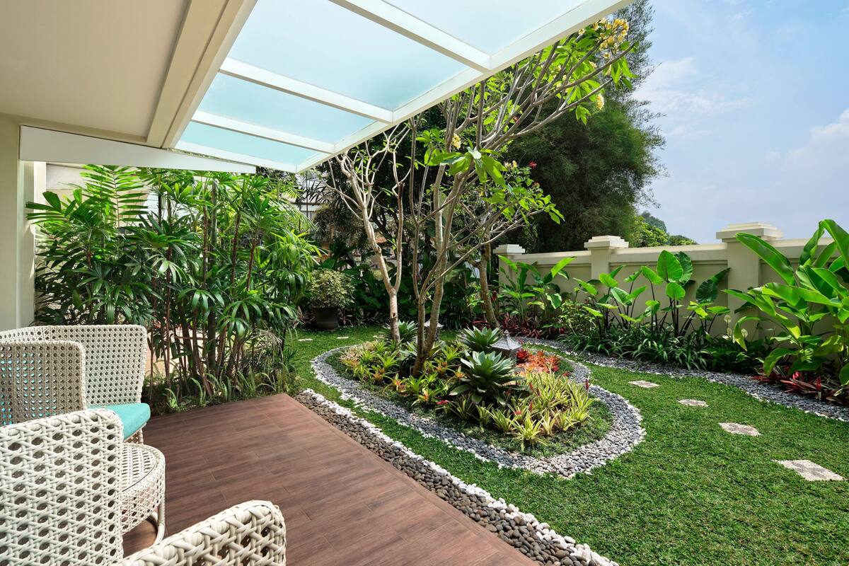 Une terrasse avec des meubles en osier, un petit jardin avec différentes plantes et une terrasse en bois.
