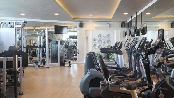 Un gimnasio con diversas máquinas de ejercicio, incluyendo cintas de correr y equipo de levantamiento de pesas.