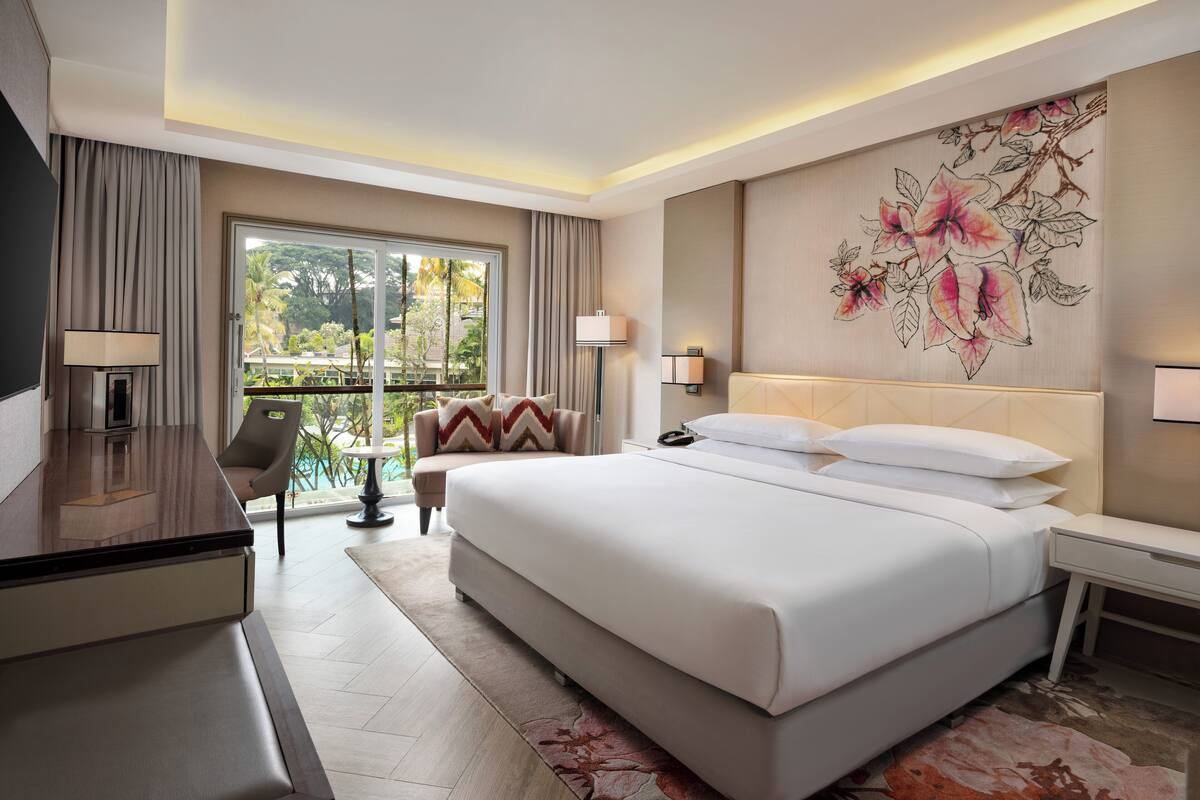 Une chambre d’hôtel moderne, dotée d’un grand lit, d’un bureau, d’une chaise et offrant une vue sur l’extérieur.