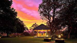 A gazebo with a tiled roof, surrounded by grass and trees, with a pathway leading to it. - Sheraton Bandung Hotel & Towers (Bandung)