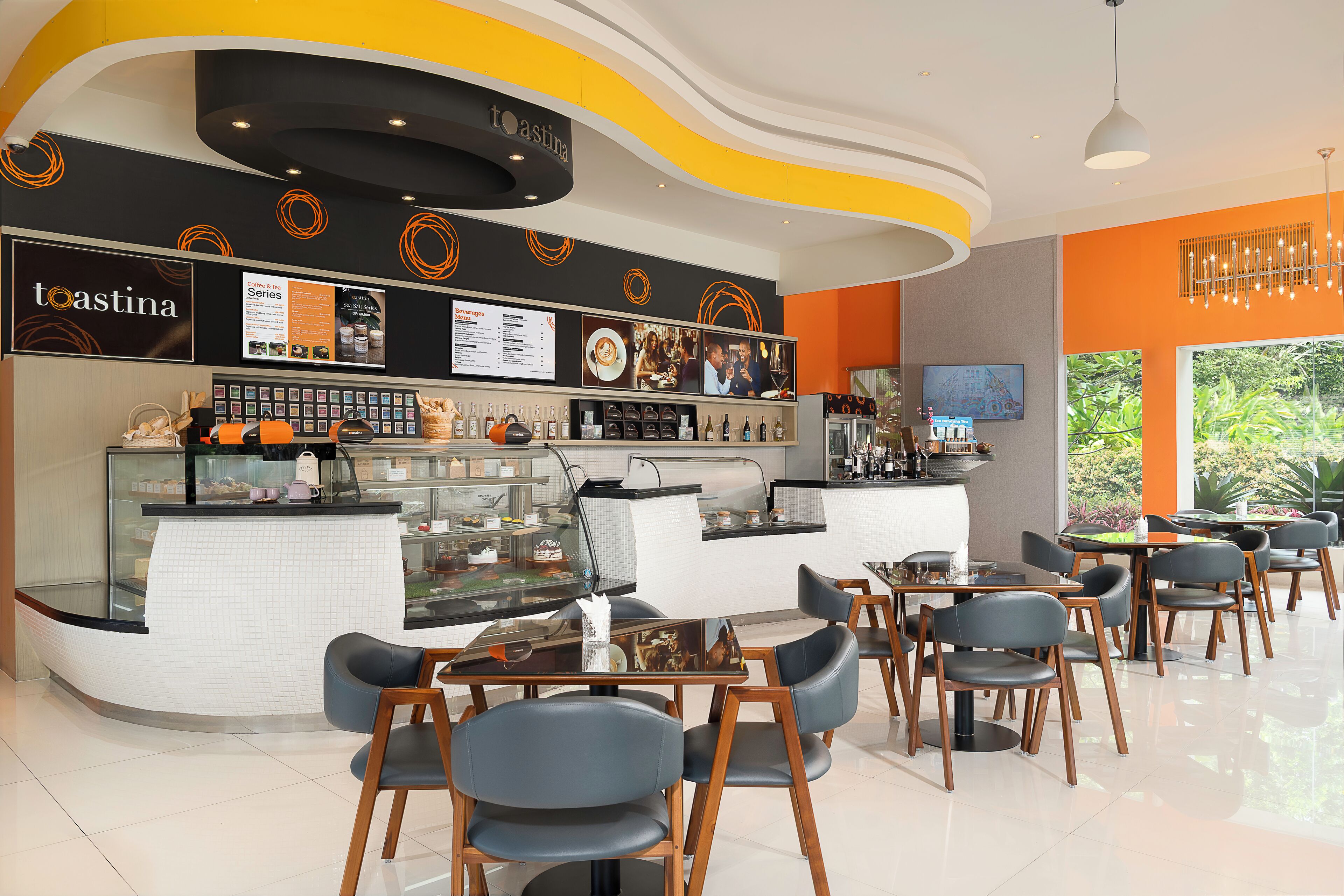 Un café moderne avec un comptoir incurvé, un espace salon et un tableau affichant le menu.