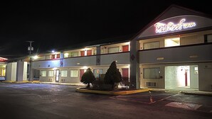 A motel with a neon sign, multiple floors, and a parking lot. - Red Roof Inn Somerset, PA (Somerset)