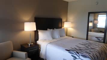 A hotel room with a bed, two bedside lamps, a nightstand, a chair, and a large mirror.