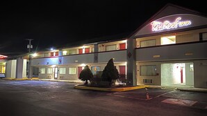 A motel with a neon sign, multiple floors, and a parking lot. - Red Roof Inn Somerset, PA (Somerset)