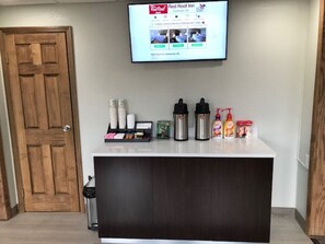 A reception desk with a flat-screen TV displaying the Red Roof Inn website, a coffee maker, a water dispenser, and a small selection of toiletries. - Red Roof Inn Somerset, PA (Somerset)