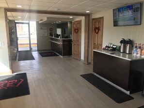Un hall de hotel con recepción, estación de café y vistas panorámicas de la ciudad.