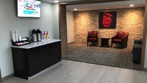 A reception area with a counter, a TV, and a Red Roof Inn sign. There are two leather chairs and a small table. - Red Roof Inn Somerset, PA (Somerset)