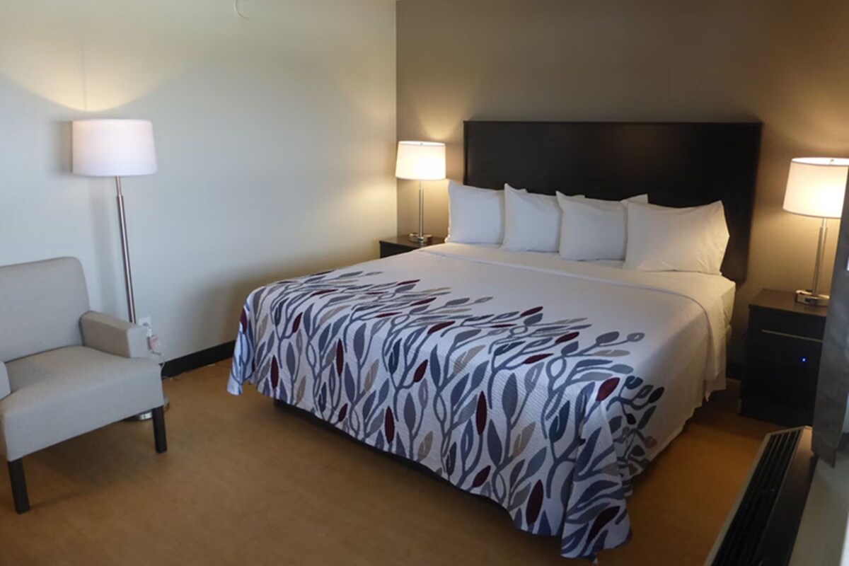 A hotel room with a large bed, two bedside tables with lamps, a chair, and a floor lamp.
