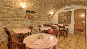 A restaurant with stone walls, wooden tables, and chairs. - Timhotel Invalides Eiffel (Paris)