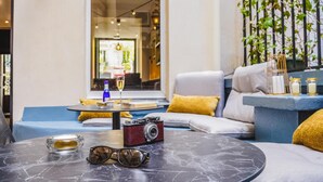 A modern living room with a curved sofa, a round coffee table, and a vintage camera. - Timhotel Invalides Eiffel (Paris)