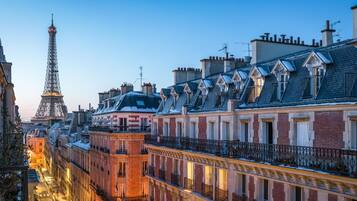A row of Parisian buildings with a view of the Eiffel Tower in the background.
