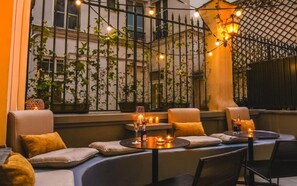 A cozy indoor seating area with cushioned benches, a table with candles and a bottle, and string lights.