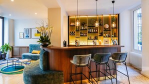 A modern bar area with a wooden counter, three bar stools, and a variety of bottles and glasses. - Timhotel Invalides Eiffel (Paris)