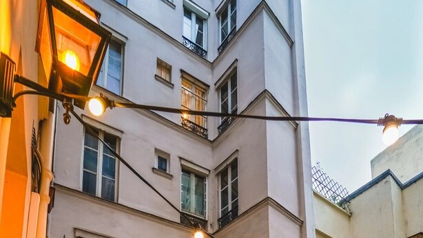An outdoor seating area with a fire pit, cushioned seating, and string lights. - Timhotel Invalides Eiffel (Paris)