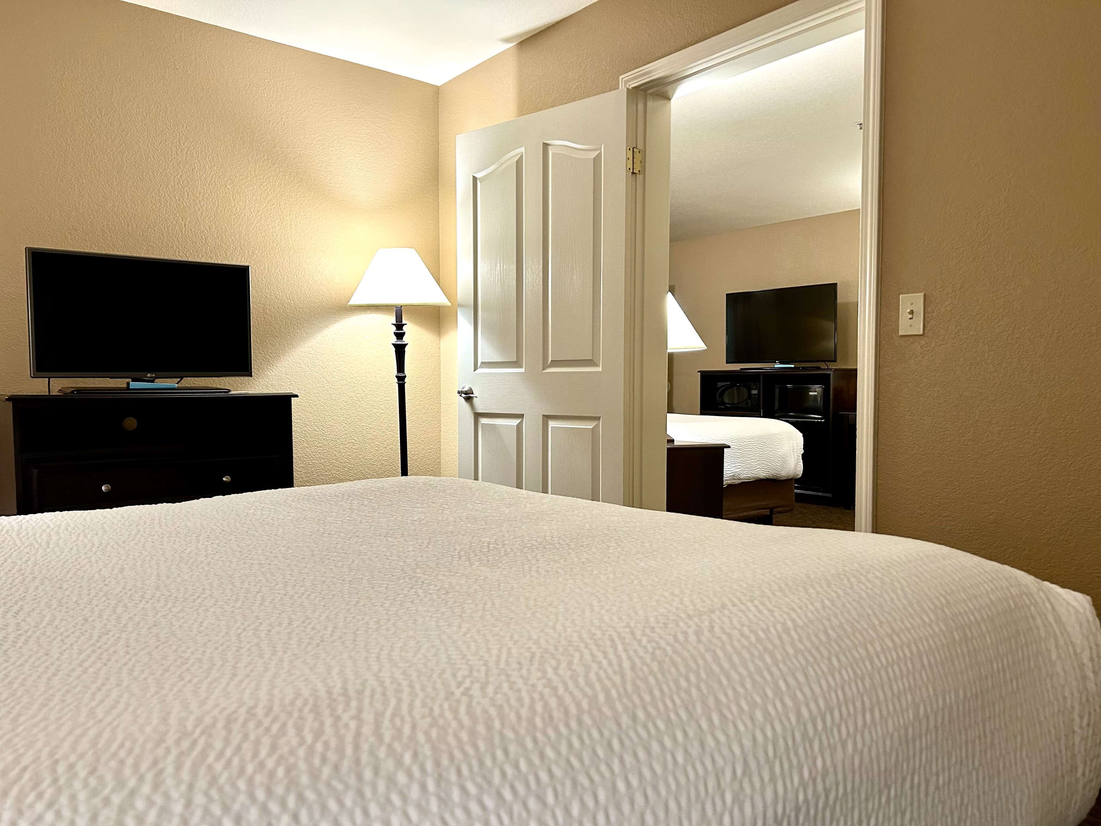 Habitación de hotel con una cama grande, televisor de pantalla plana, escritorio con lámpara y armario.