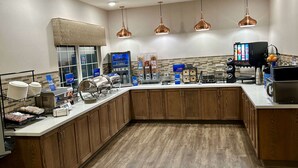 A modern kitchen with wooden cabinets, stainless steel appliances, and copper pendant lights.