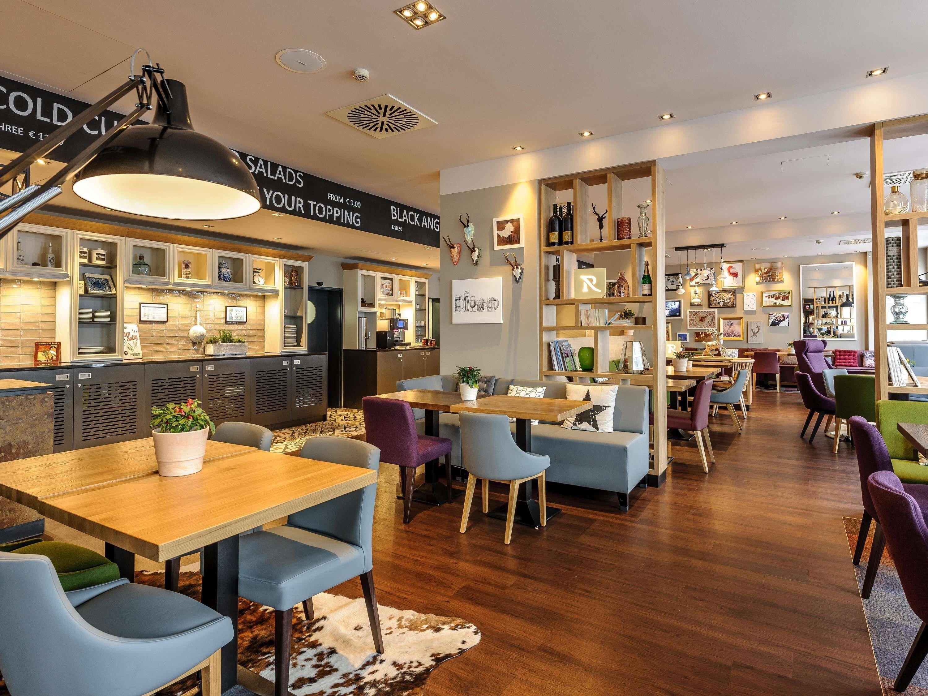 Ein Restaurant mit Barbereich, Sitzgelegenheiten an Tischen und Stühlen sowie vielfältiger Dekoration, darunter Bücherregale und Wandbilder.