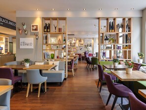 Un intérieur moderne avec des étagères en bois, des coins salon et un comptoir de restaurant bien visible.