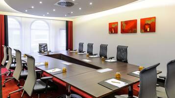 A conference room with a long table, multiple chairs, and a red carpet.