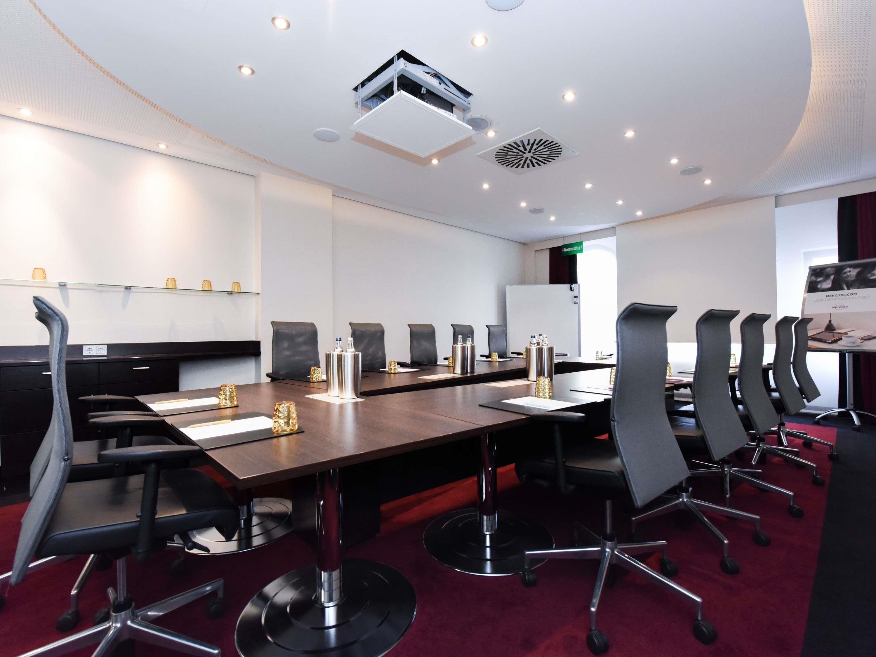 A conference room with a long table, black chairs, and a whiteboard.
