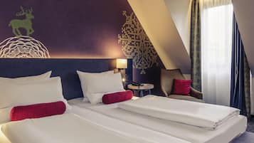 A hotel room with two beds, a wall mural, a small table with a phone, and a view of the outdoors.