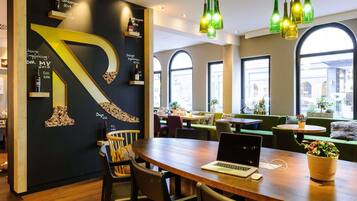 A modern restaurant interior with a large black wall featuring a prominent number '1' design, wooden tables, and green seating.