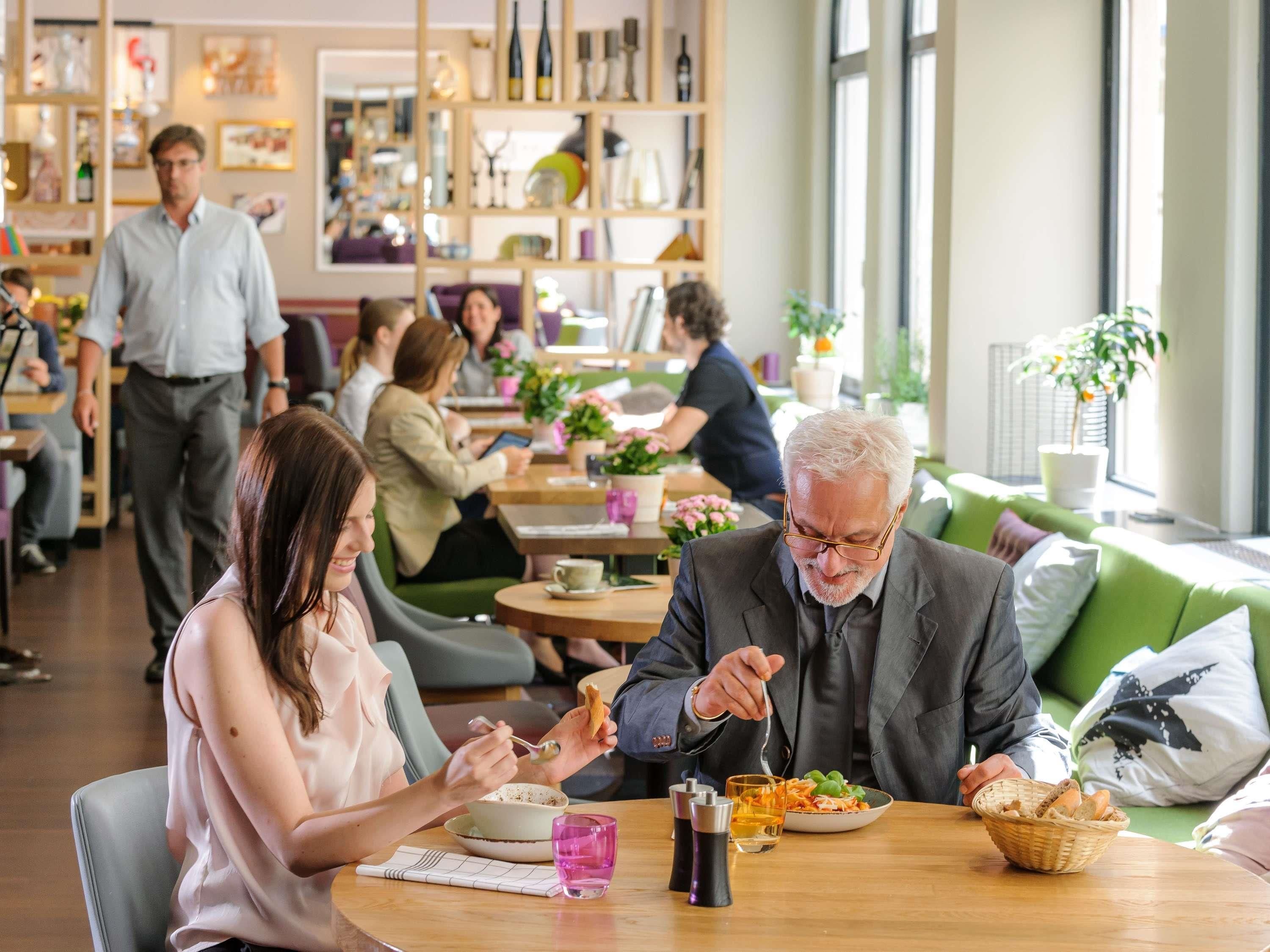 Un comedor moderno con mesas, sillas y una variedad de plantas y elementos decorativos.