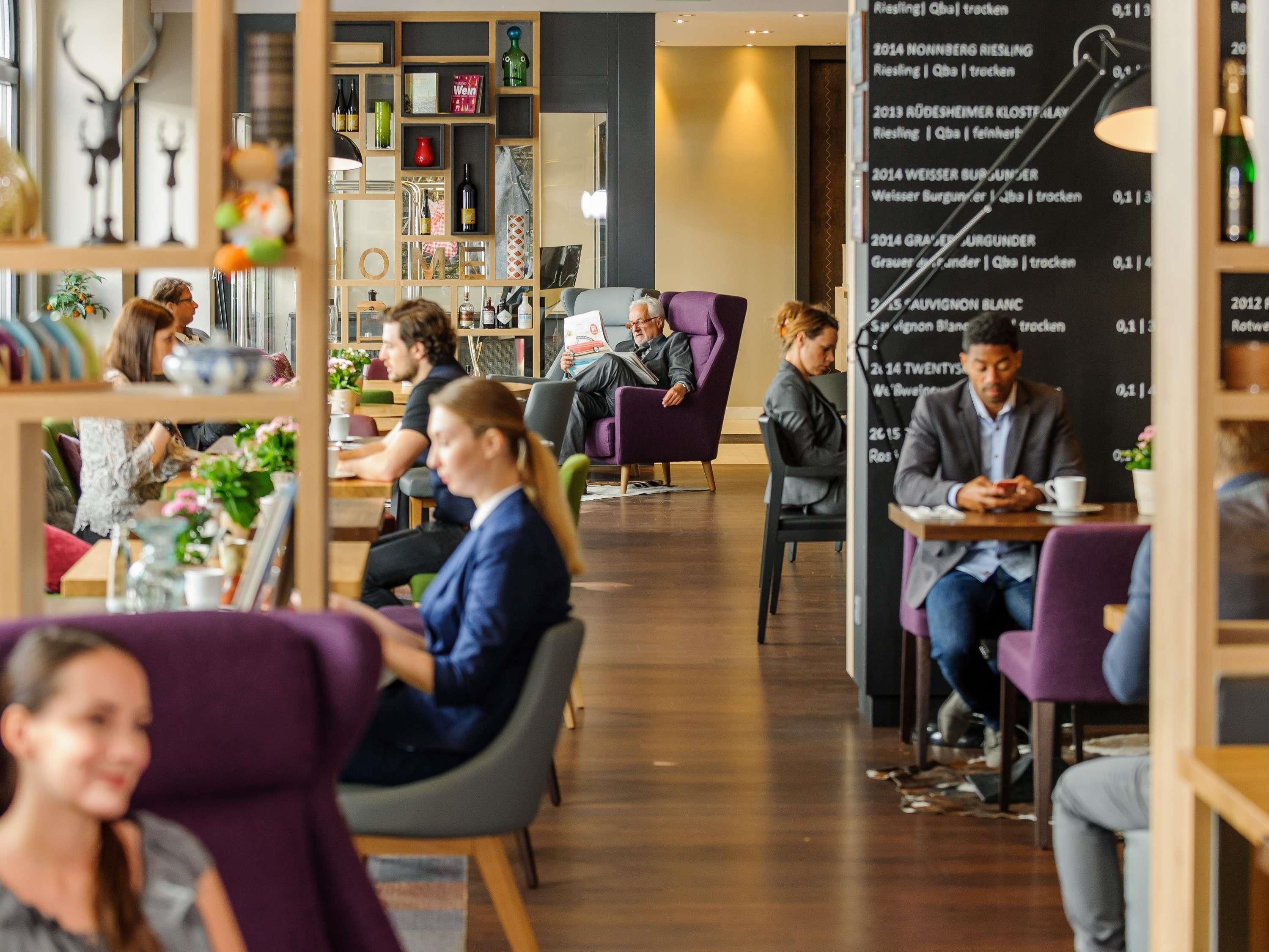 A modern cafe with wooden shelves, comfortable seating, and a menu board.