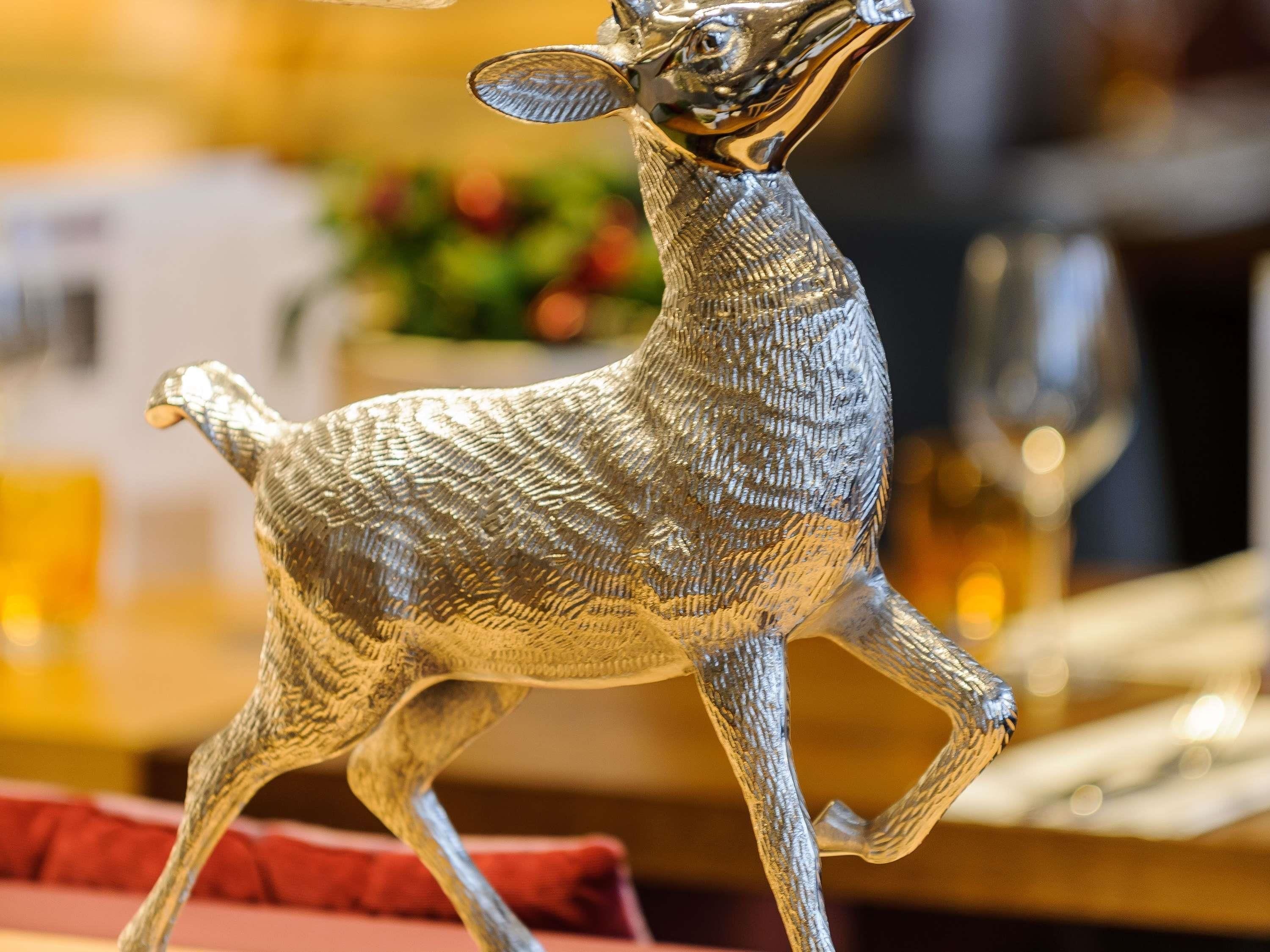 Una figurita de venado plateado sobre una mesa.