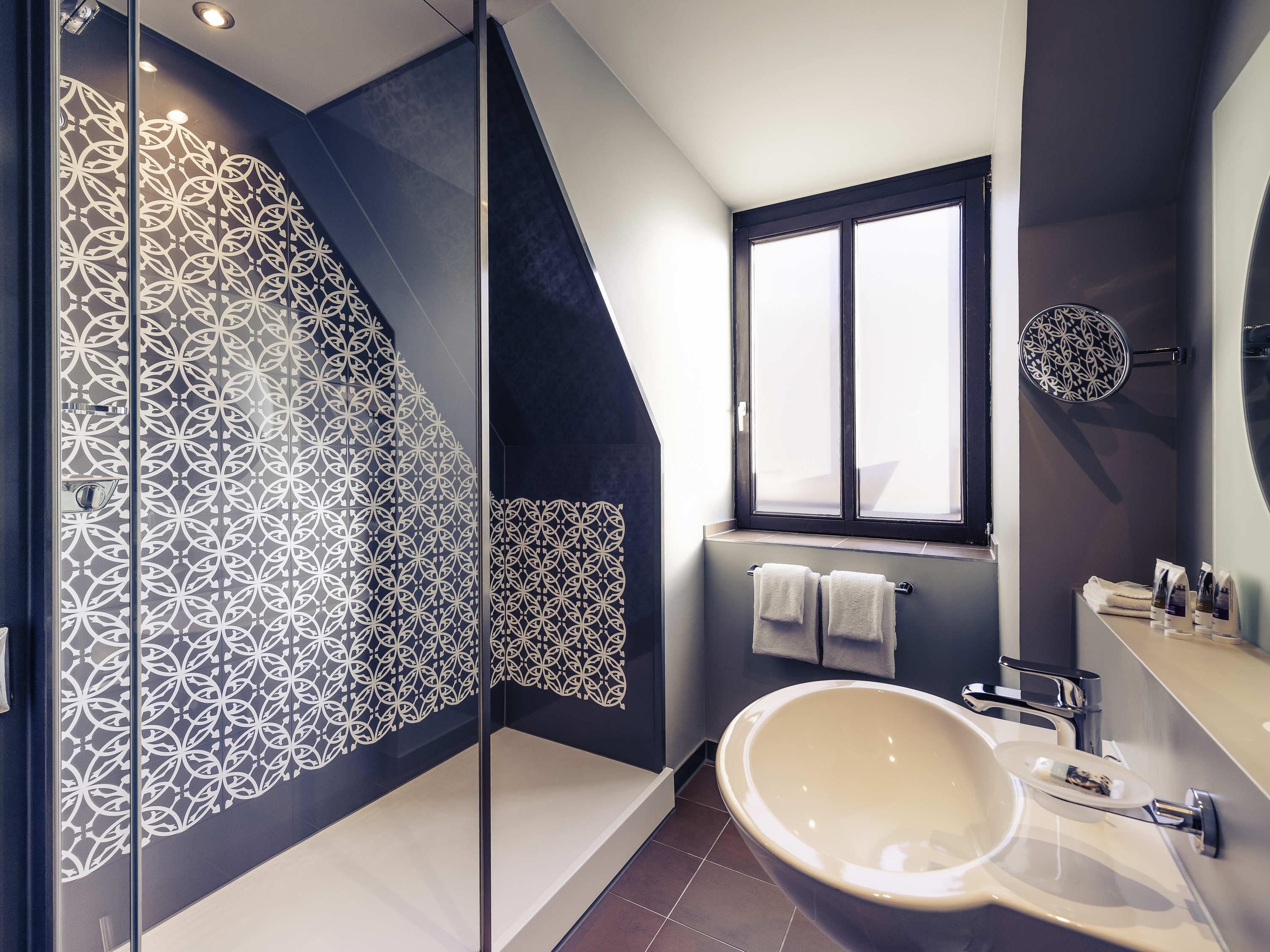 A modern bathroom with a large bathtub, a glass shower enclosure, and a window.