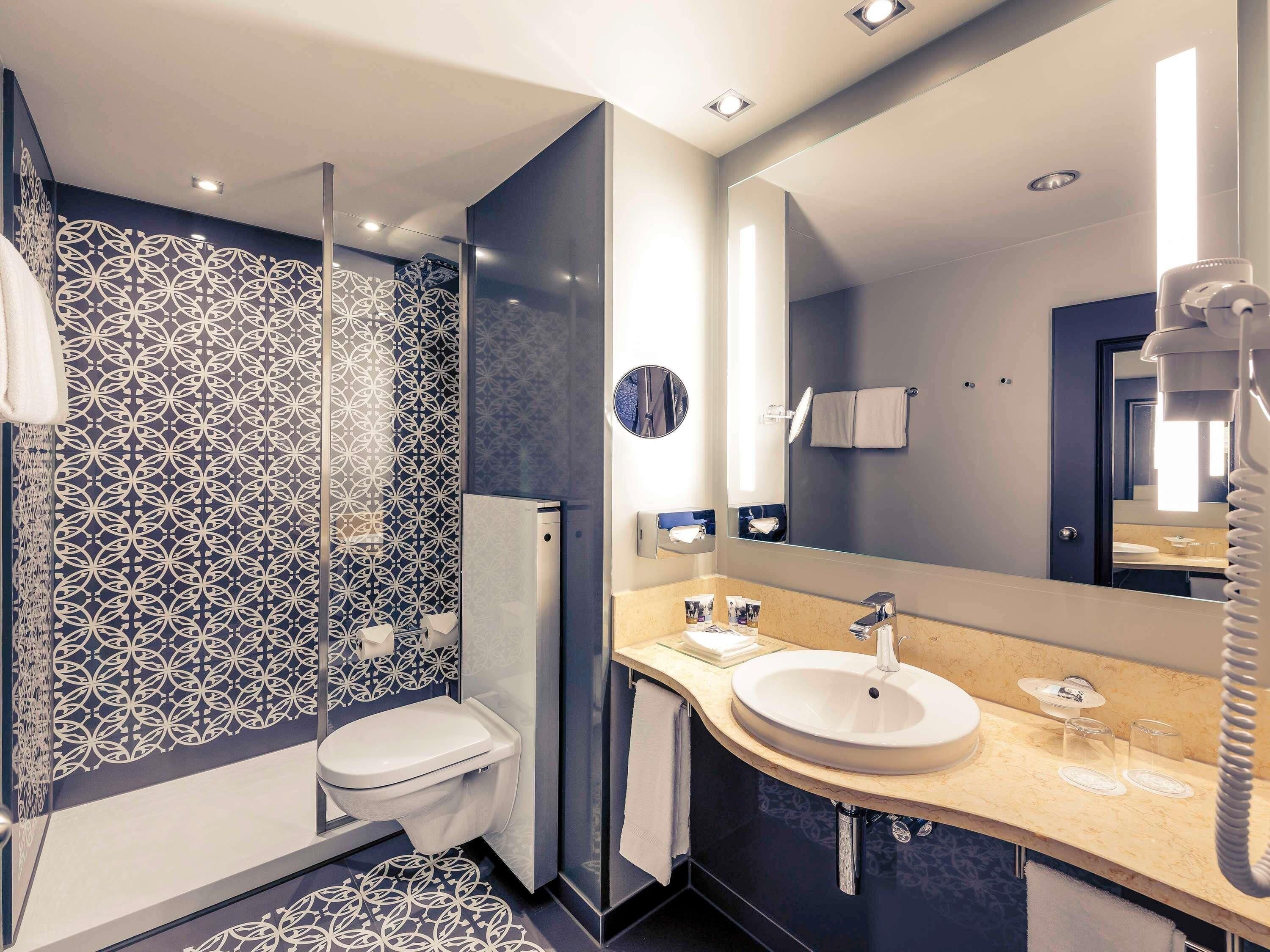 A modern bathroom with a toilet, sink, and mirror.