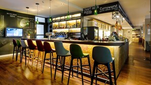 A bar area with a counter, stools, and a menu board. - Mercure Muenchen City Center (Munich)