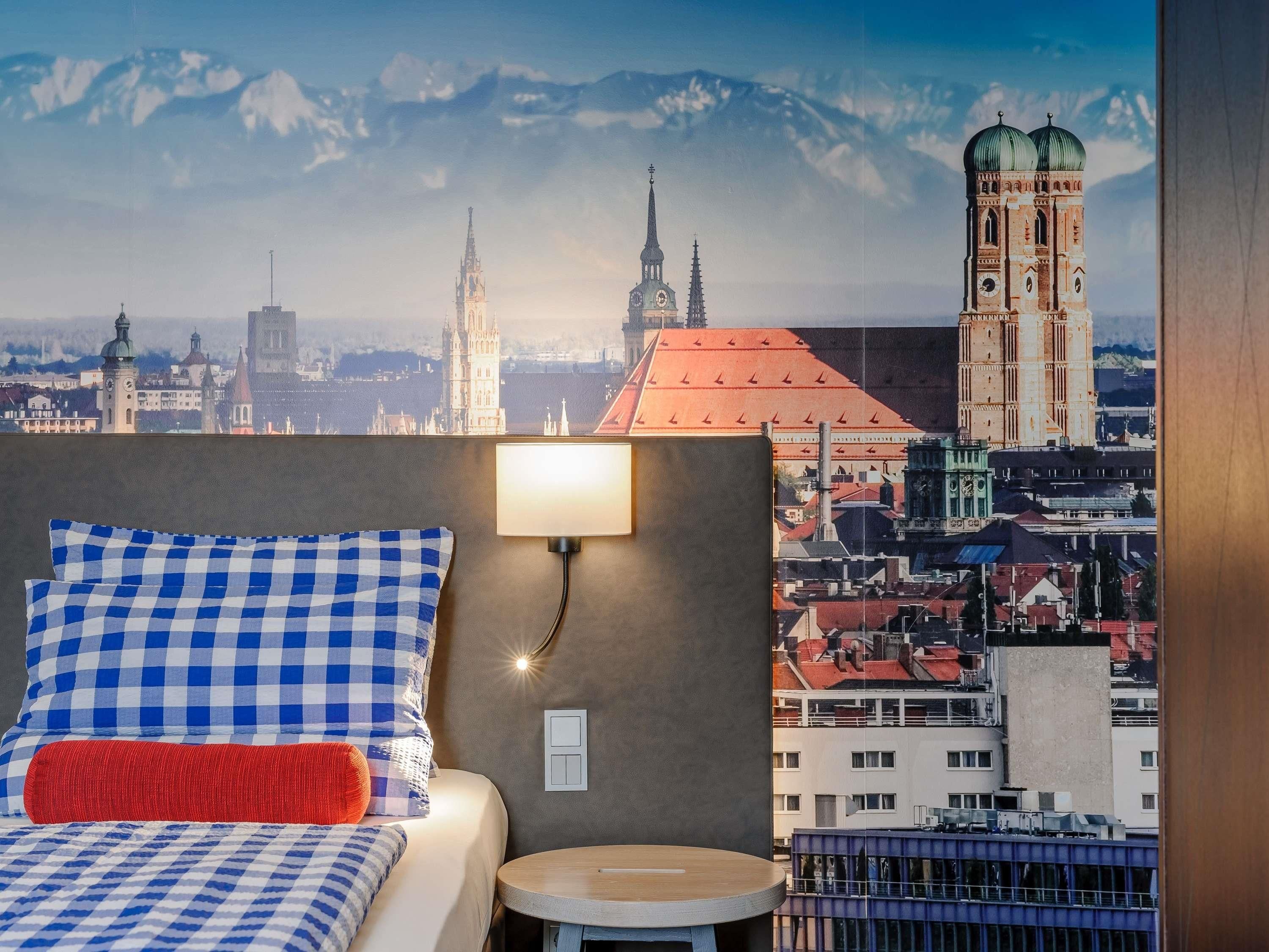 A hotel room with a bed, a round table, and a cityscape view.