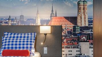 Ein Hotelzimmer mit einem Bett, einem runden Tisch und Blick auf die Stadt.