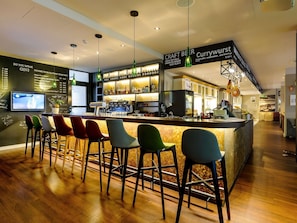 A bar area with a counter, stools, and a selection of craft beers. - Mercure Muenchen City Center (Munich)