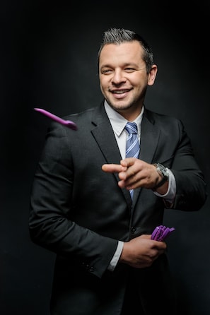 A person in a dark suit pointing with one hand and holding a purple object in the other. - Mercure Muenchen City Center (Munich)