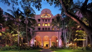 A grand hotel entrance with a central archway, surrounded by lush greenery and palm trees. - The Royal Hawaiian, a Luxury Collection Resort, Waikiki (Honolulu)